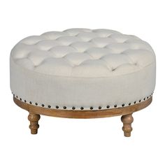 a white ottoman sitting on top of a wooden stand with studded trimmings