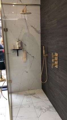 a bathroom with marble walls and flooring, shower head and hand held shower faucet