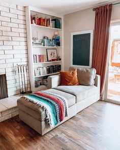 a living room with a couch, bookshelf and fire place in it's center