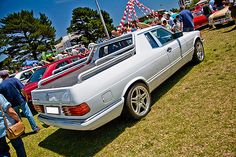 several cars are parked on the grass at a car show with people standing around them