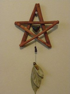 a wooden star hanging on the wall next to a feather and bead charm necklace