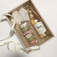 an open gift box containing two bottles of wine and macaroni and cheese wrapped in white ribbon