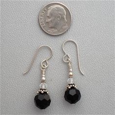 a pair of black glass beaded earrings next to a penny