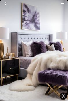 a bed with purple and white fur on top of it next to a night stand