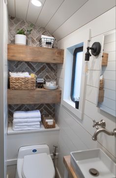 a small bathroom with shelves above the toilet