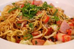 a white bowl filled with noodles, meat and veggies on top of it