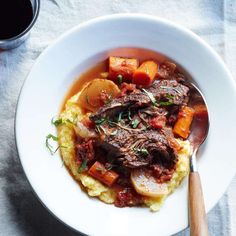 a white bowl filled with meat and potatoes