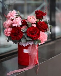 a bouquet of red and pink flowers in a red bucket