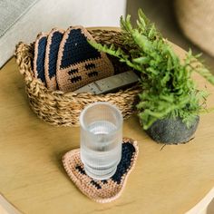 a crocheted basket with a knife and glass on it next to a potted plant