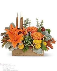 an arrangement of flowers and candles in a wooden box