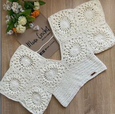 two white crocheted dishcloths on a wooden surface with flowers in the background