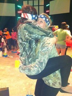 two women hugging each other in front of an audience at a dance event with flags on their heads