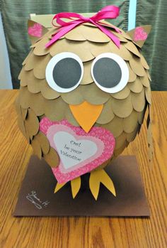 an owl made out of paper on top of a wooden table with a pink bow