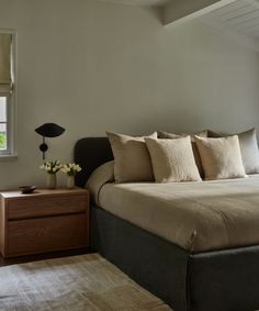 a large bed sitting next to a window in a bedroom on top of a rug