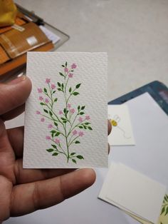 a hand holding a piece of paper with pink flowers on it