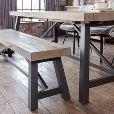 a wooden bench sitting under a window next to a table