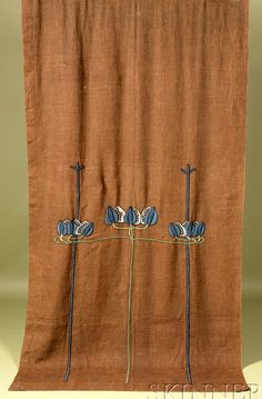 an orange curtain with three blue flowers hanging from it's center, on a white table