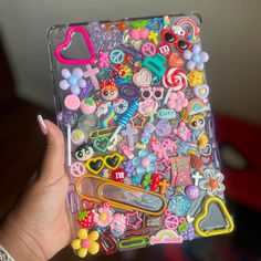 a person holding up a case filled with lots of stickers and magnets on it