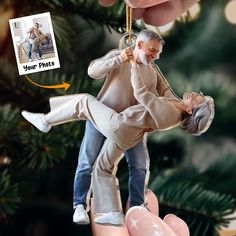 an ornament hanging from a christmas tree with a man holding a woman's leg