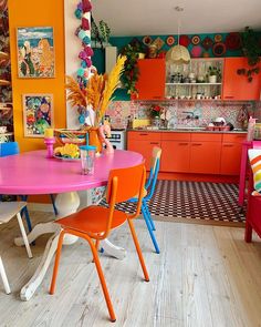 an orange and pink table in a brightly colored kitchen with lots of colorful decor on the walls