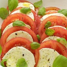 tomatoes and mozzarella with basil leaves in a white bowl