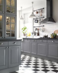 a kitchen with gray cabinets and black and white checkered flooring on the tile