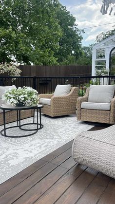 an outdoor living area with wicker furniture and white flowers on the table in front of it