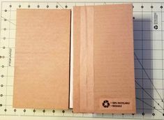 two brown notebooks sitting next to each other on a piece of paper and ruler