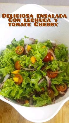 a white bowl filled with lettuce and tomatoes on top of a wooden table