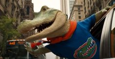 a stuffed alligator sticking its head out the window of a car in front of a bus