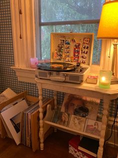 an old record player sits on top of a table next to a lamp and books