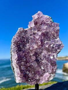 a purple rock sitting on top of a wooden table next to the ocean