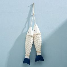 two white fish hanging on a rope against a blue wall