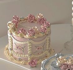 a pink and gold decorated cake sitting on top of a table next to a plate