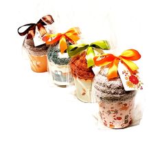 three small jars with bows on them sitting side by side in plastic bags, each containing different types of desserts