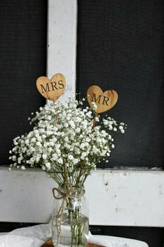 a vase filled with baby's breath sitting on top of a table next to a window