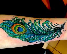 a colorful peacock feather tattoo on the arm