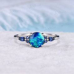 7mm Round Galaxy Blue Opal Engagement Ring Sterling Silver Cluster Blue Sapphire Ring Unique Anniversary Gift Blue Fire Opal Promise Rings 30 days non-hassle return policy. For returned items, there may be handcrafting and shipping fee deducted. DETAILS: - Material : 925 Sterling Silver (Hypoallergenic, Nickel Free, Tarnish Resistant)Solid 14k/18k gold,platinum PLEASE choose silver or platinum if you are allergic to nickel. - Main stone : 7mm Round cut blue opal - Accent Stone : blue sapphire - Blue Opal Rings For Anniversary, Blue Opal Promise Ring, Blue Opal Ring Gift, Blue Opal Anniversary Rings, Blue Opal Jewelry For Anniversary, Blue Round Gemstone Jewelry, Blue Opal Round Ring, Blue Round Band Jewelry Gift, Blue Round Opal Ring