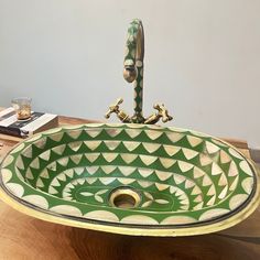 a green and white sink sitting on top of a wooden table next to a book