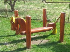 a wooden horse shaped play set in the grass