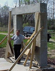 a man standing in front of a wooden structure that has been built into the ground