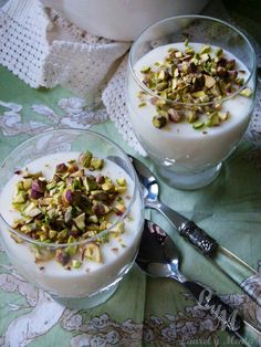 two bowls filled with yogurt and pistachio toppings on a table