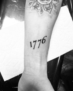 a person with a tattoo on their arm that reads, 1876 and has the number seventy seven