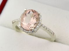 an engagement ring with a pink stone surrounded by diamonds