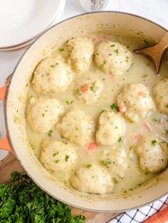 a pot filled with meatballs and gravy on top of a wooden cutting board