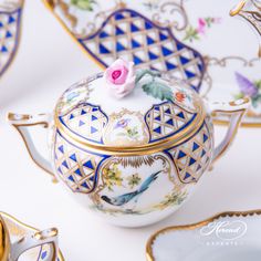 a tea pot with a pink rose on the top and gold trimming around it