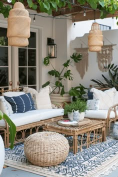 an outdoor living room with wicker furniture and plants on the rugs in front of it