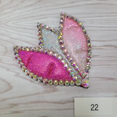 two pink and silver hair clips with sequins on them sitting on a wooden surface