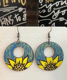 This is a pair of Handcrafted Woodburn 2.5" Sunflower earrings with blue and yellow paint and a yellow color wash tint. Nickelfree ear wires. Lightweight Sealed Artsy Yellow Earrings For Pierced Ears, Artistic Hand Painted Yellow Earrings, Artistic Adjustable Yellow Earrings, Adjustable Artistic Yellow Earrings, Hand Painted Yellow Artsy Earrings, Yellow Hand Painted Artsy Earrings, Artsy Yellow Jewelry With Ear Wire, Artistic Handmade Yellow Earrings, Hand Painted Yellow Earrings For Summer