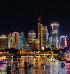 the city is lit up at night with bright lights on it's buildings and boats in the water